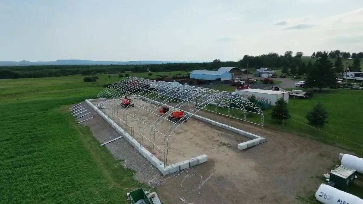 Aerial view of a long steel building frame on a farm site