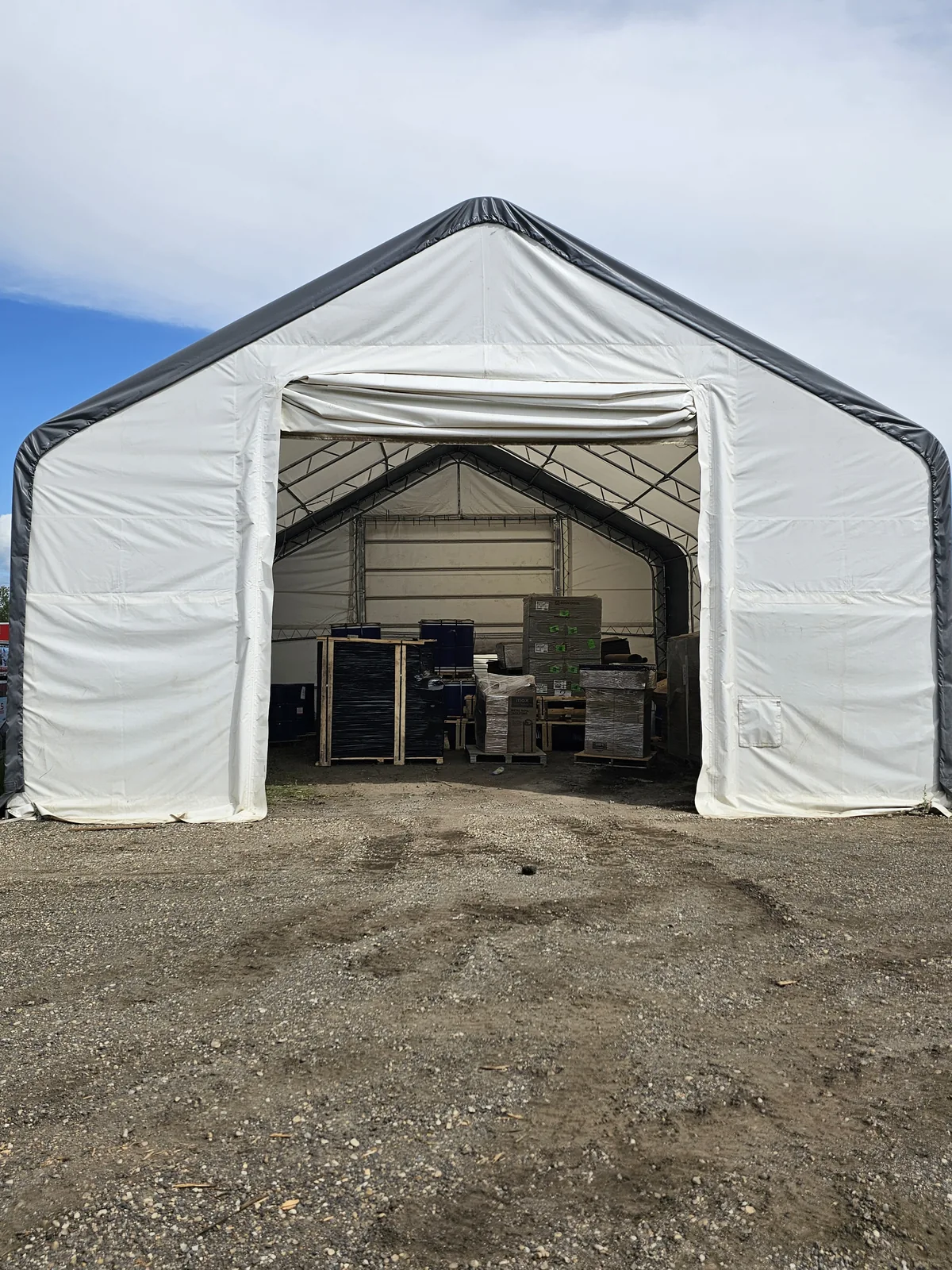 Open entrance of a white fabric building with stored materials inside