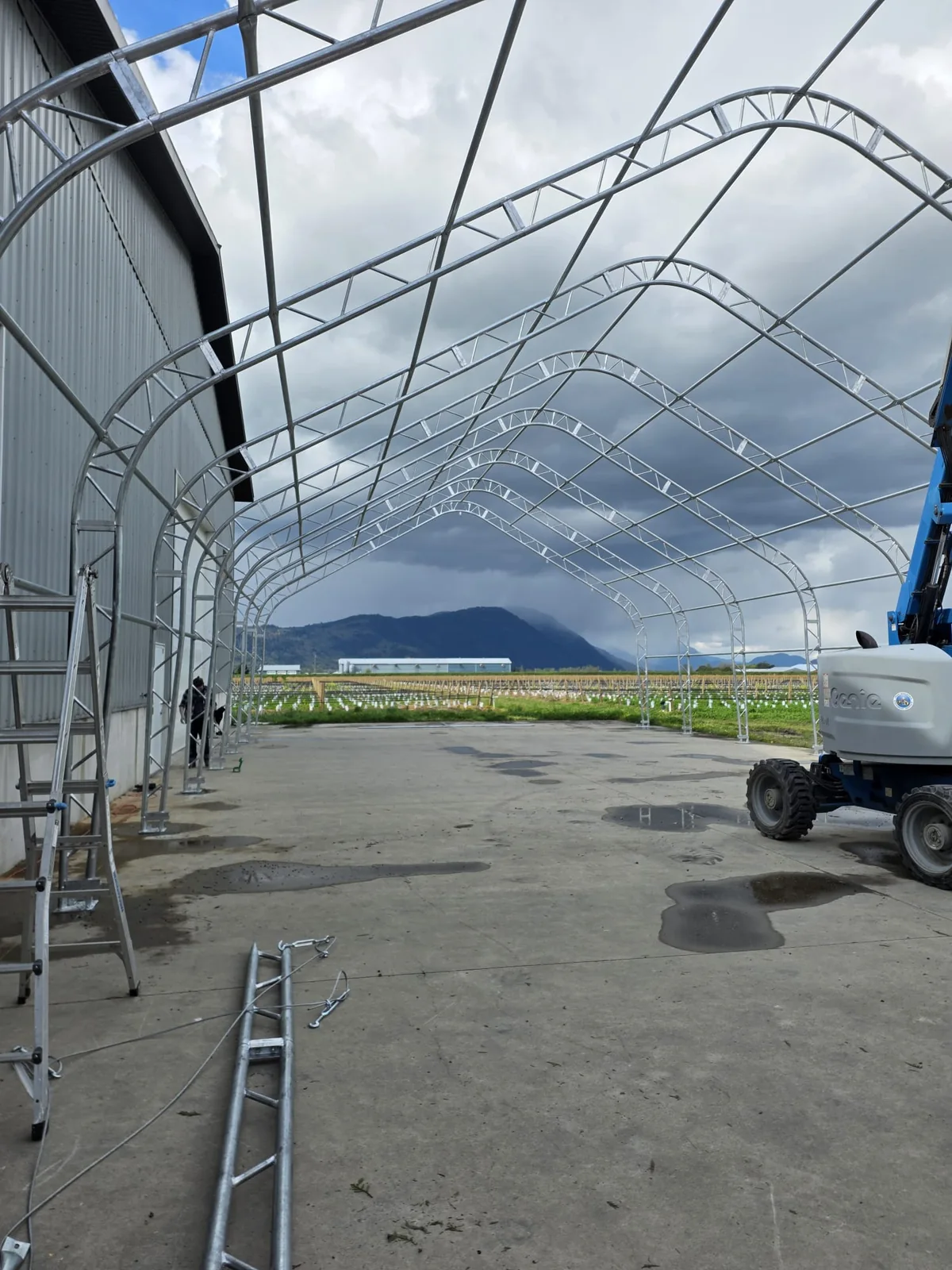 View through an uncovered steel frame alongside a metal building