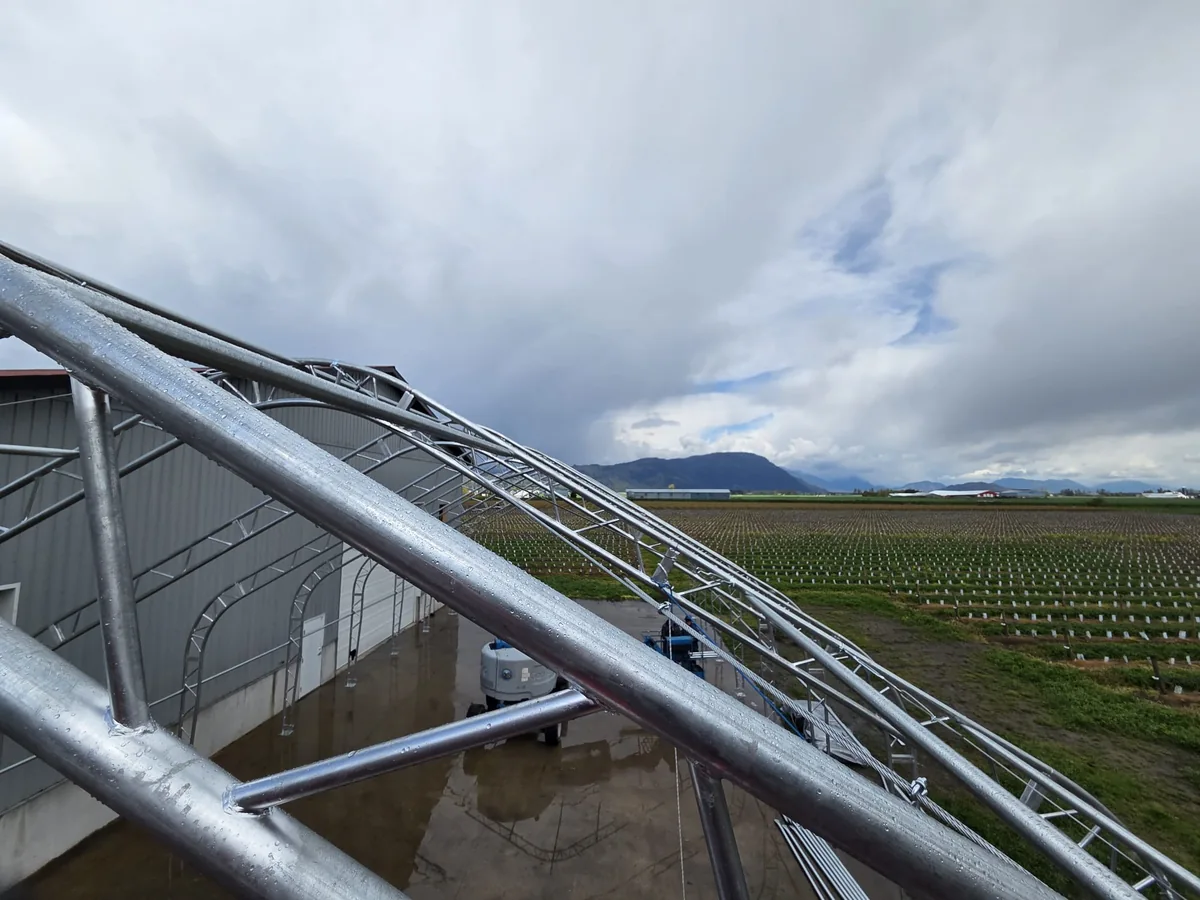 Close view along steel truss members with fields beyond